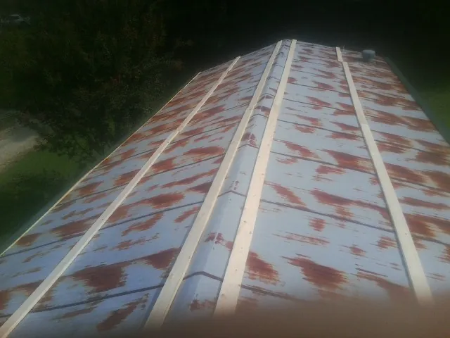 Rusted metal roof panels with new wood purlins before replacement — Storm Damage Roof Repair in Brimfield by Roofing Brothers