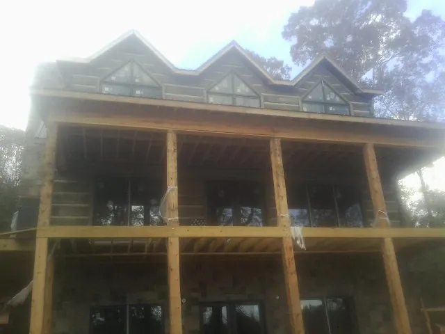Dormers and porch framing on a large log home under construction — Roof Coating work by our crew in Brimfield