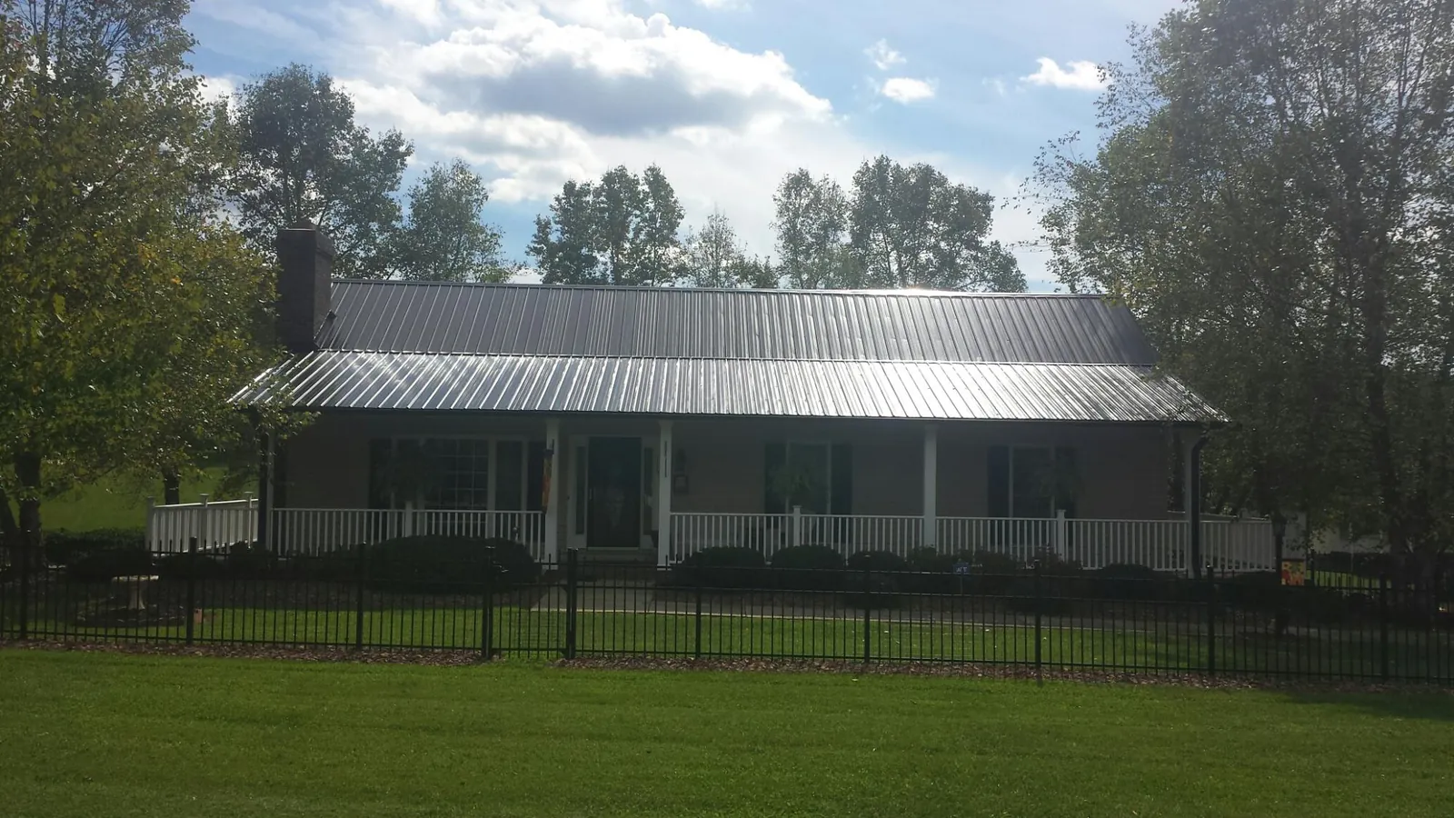 Gray metal roof on a brick ranch with a full width front porch — Gutter Guard Installation work by our crew in Brimfield