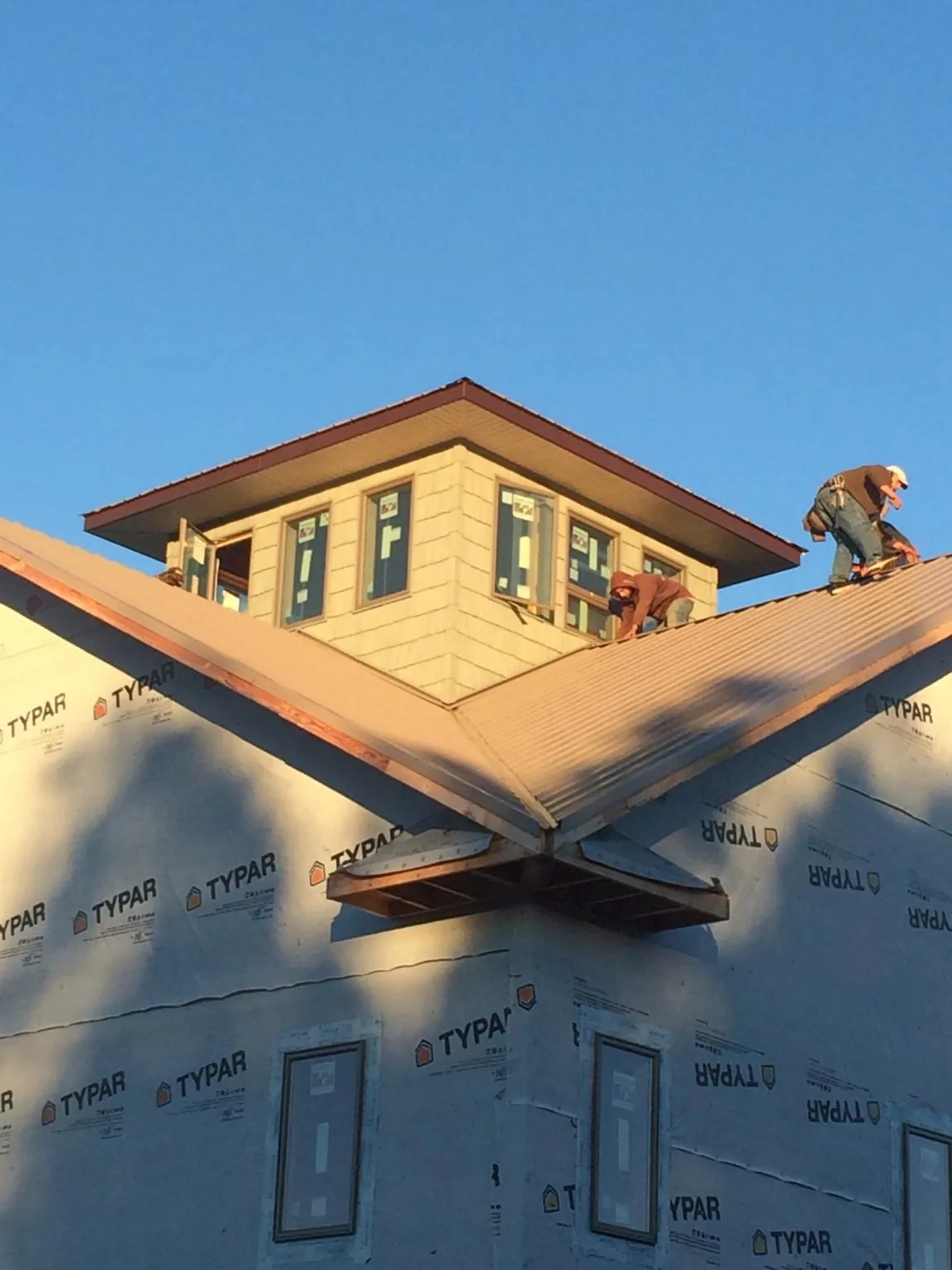 Roofers working around a rooftop cupola on a new metal roof at sunset — Roof Waterproofing in Brimfield by Roofing Brothers